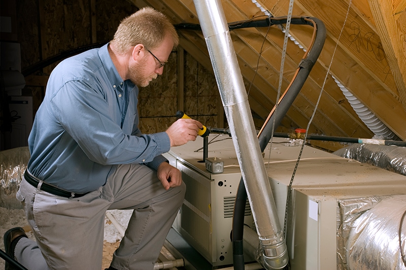 Technician performing furnace maintenance in El Dorado, KS, before winter. Don's Heating & Air blog image.